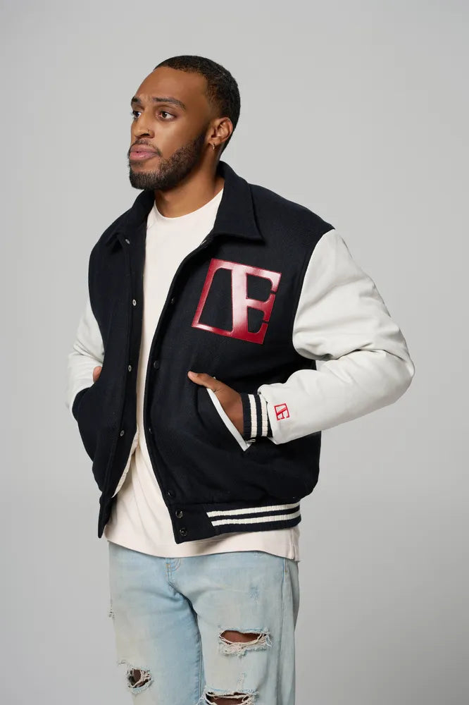a man is wearing letterman jacket in navy blue color with red etn logo