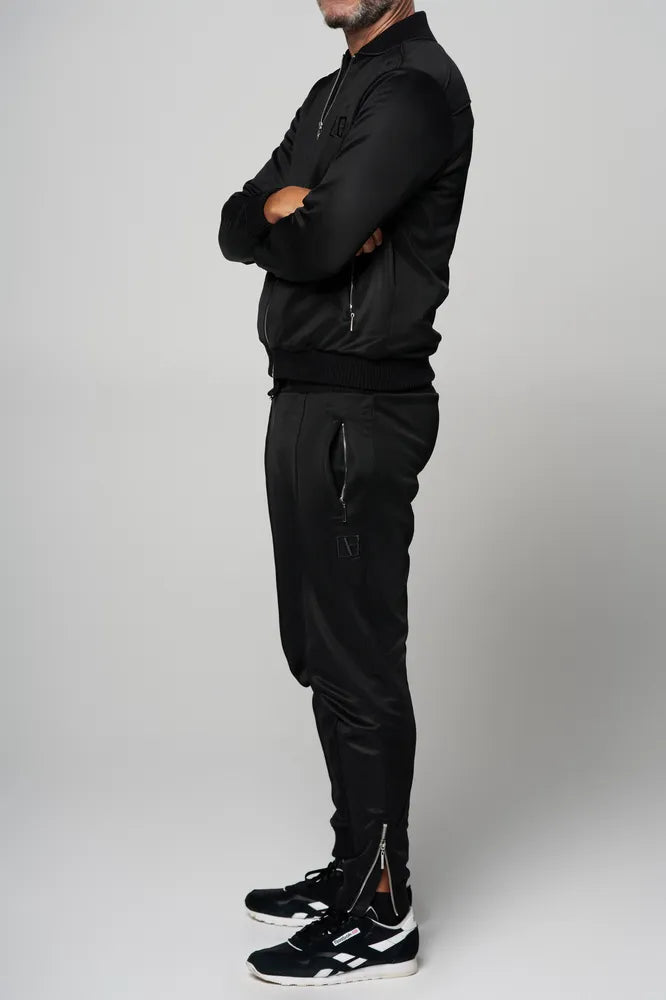a man is standing side by wearing a black tracksuit