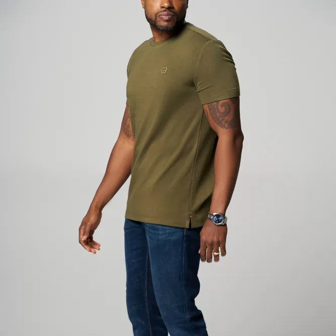 a man is wearing a forest green t shirt with blue jeans
