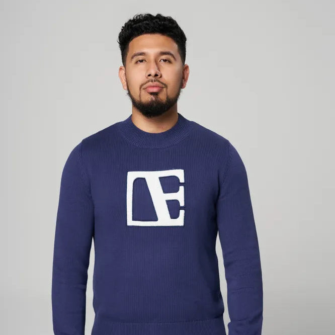 a man is wearing blue sweater standing 