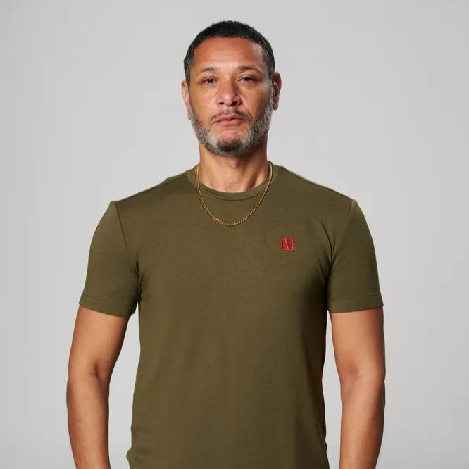 a man is wearing forest green t shirt with red logo